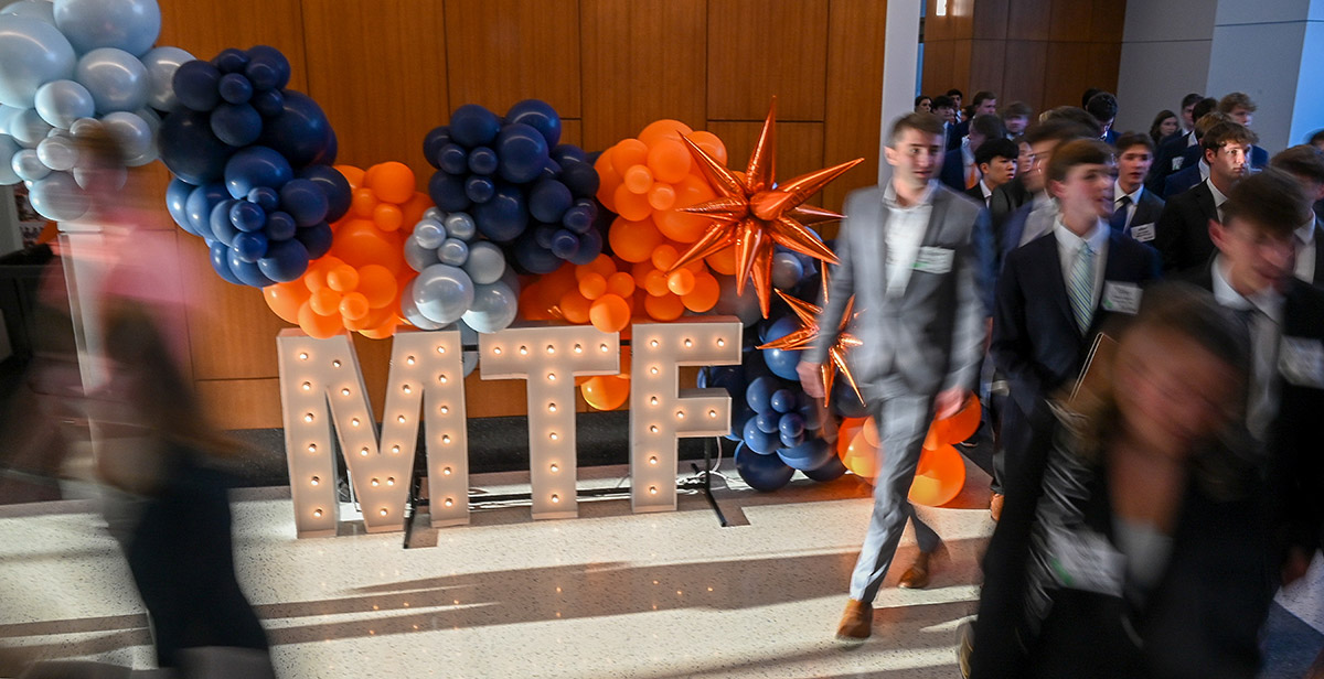 Auburn School of Accountancy’s Meet the Firms event featuring many college students walking past letters that spell out MTF illuminated by small lightbulbs alongside the school's colorful decorative balloons