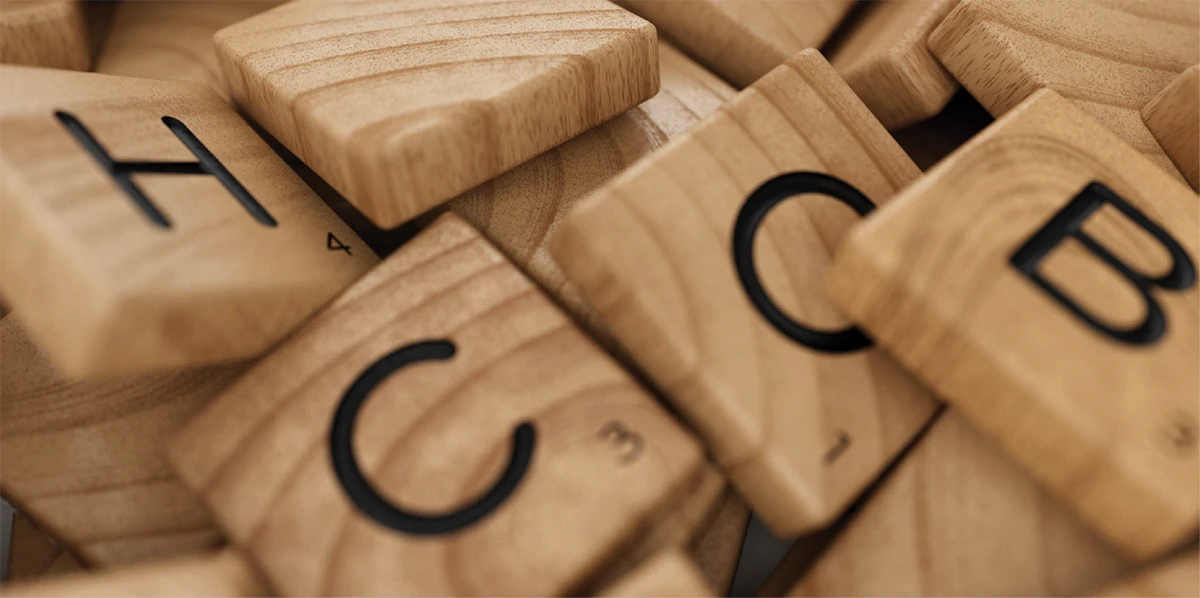 Close-up of scattered wooden letter tiles from a word game.
