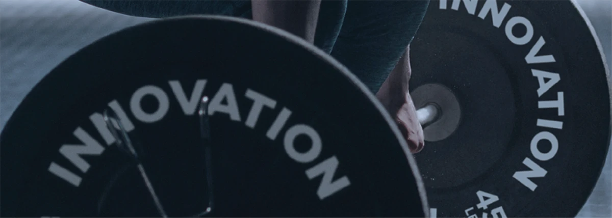 A person lifts weights with plates labeled innovation.