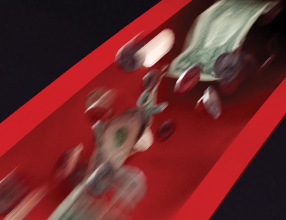 Blurred dollar bills and coins fall through a red chute.